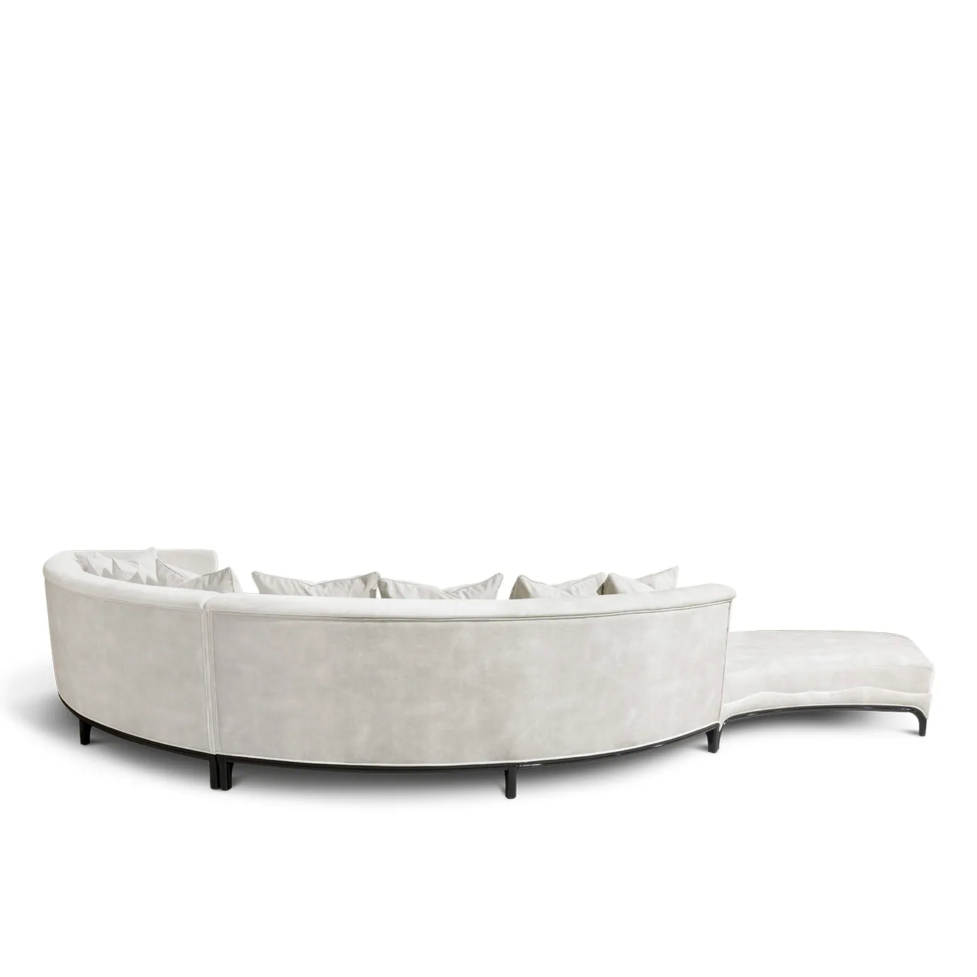 Back view of the Heavenly Sofa showcasing its sweeping curve, light upholstery, numerous cushions, and dark leg details.