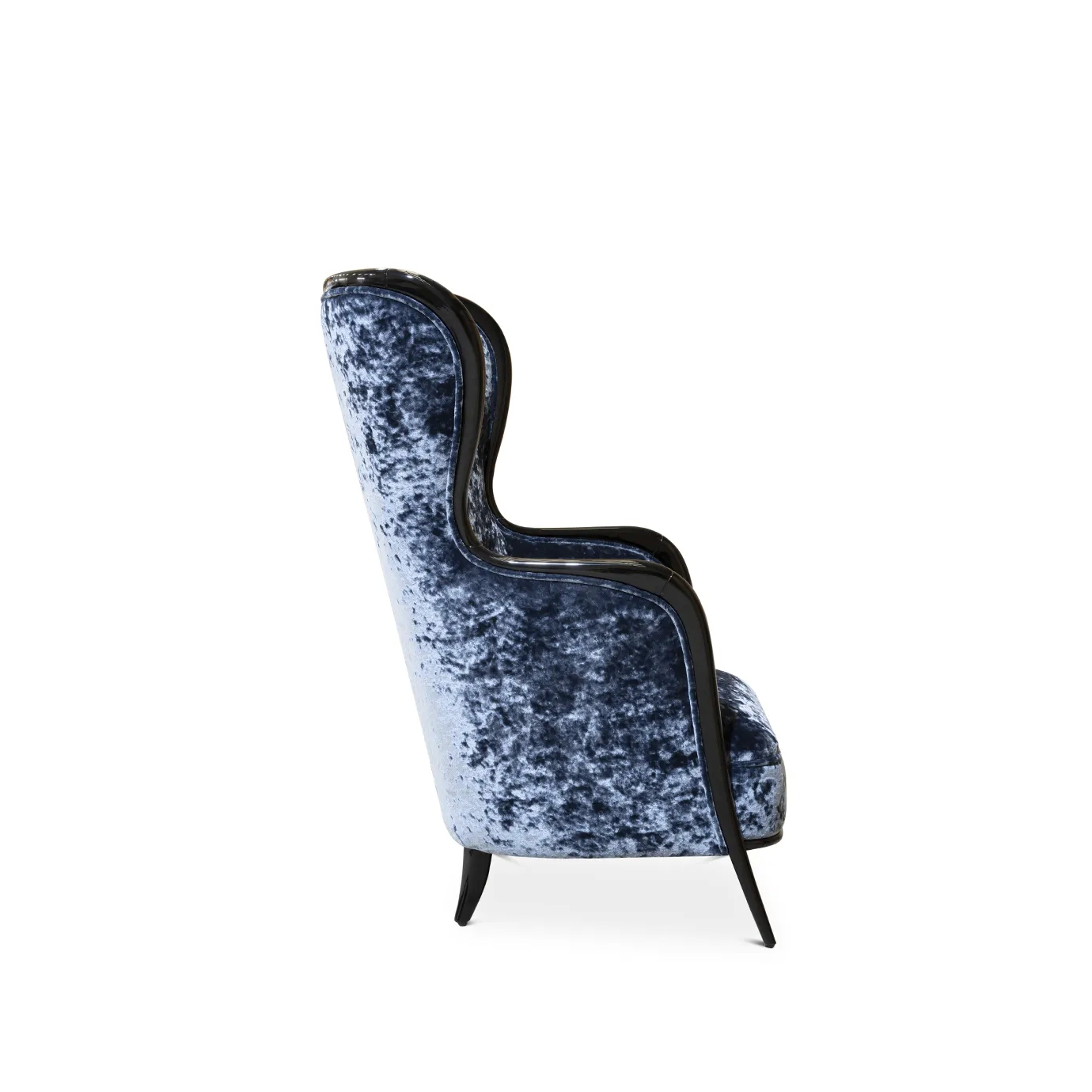 Side view of the Nudesse Chair showing its curved high back, plush velvet upholstery, and dark wood trim.