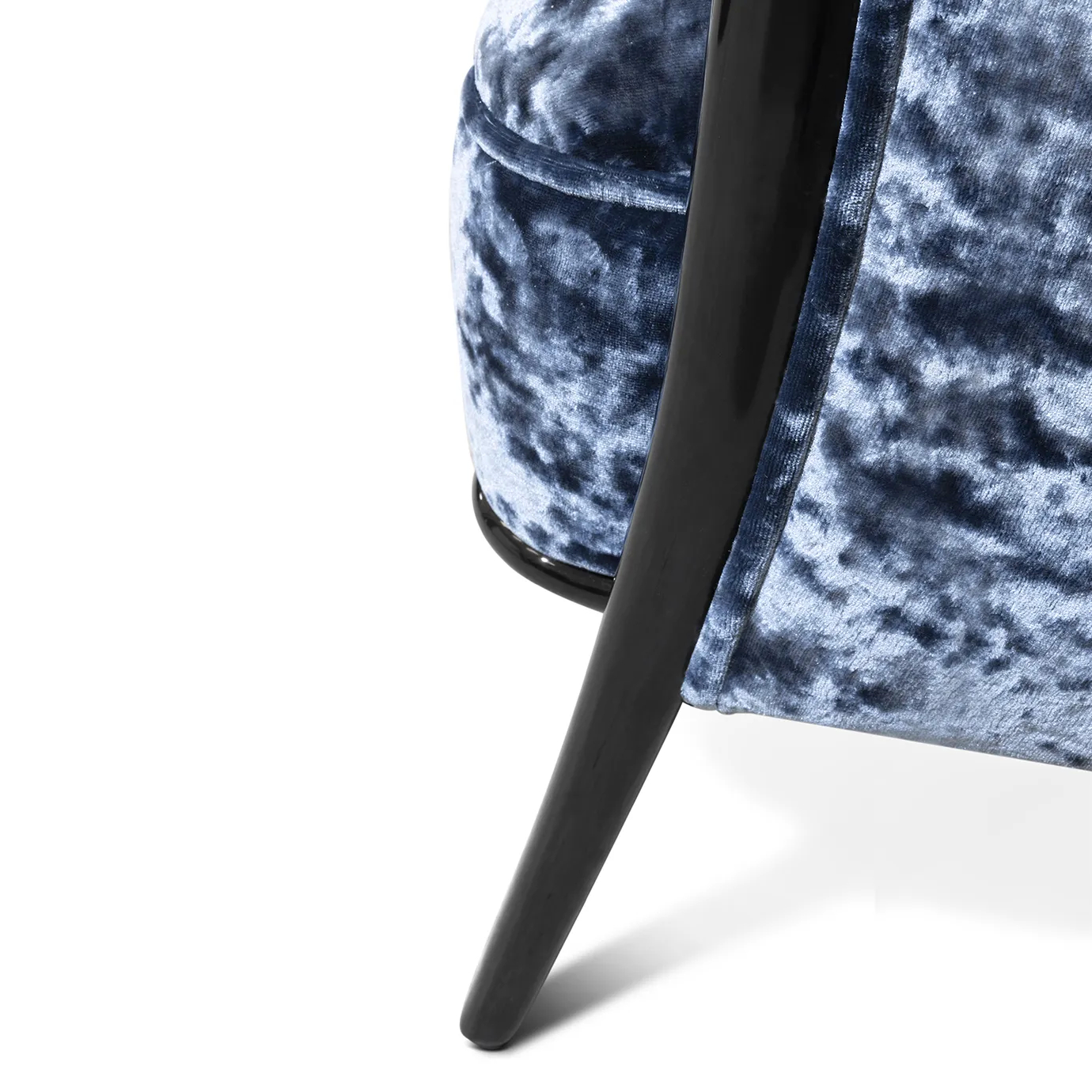 Close-up on the Nudesse Chair leg, showcasing its sleek, dark wood and how it meets the plush blue velvet upholstery.