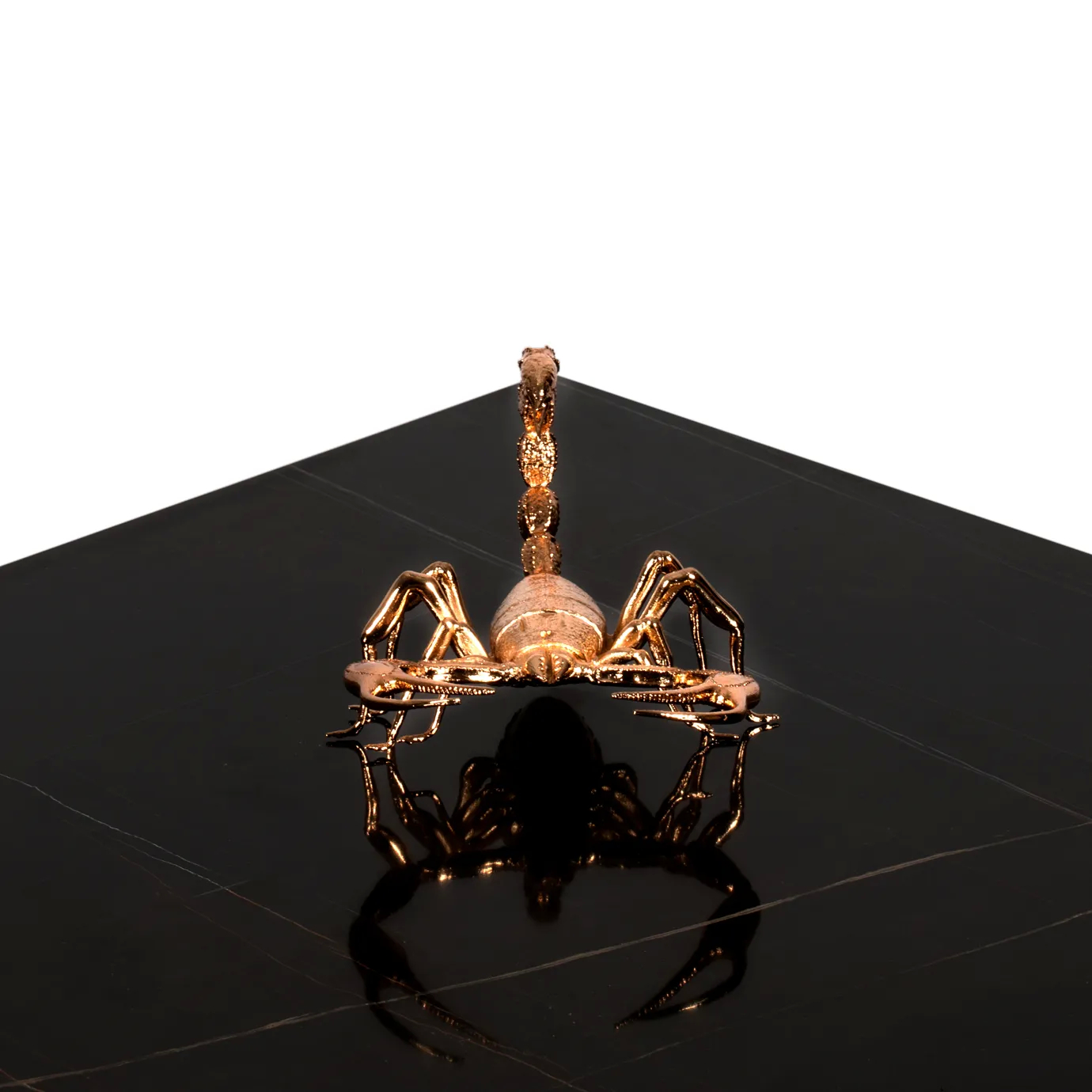 Top-down view of a golden scorpion sculpture on a black marble Metamorphosis table.