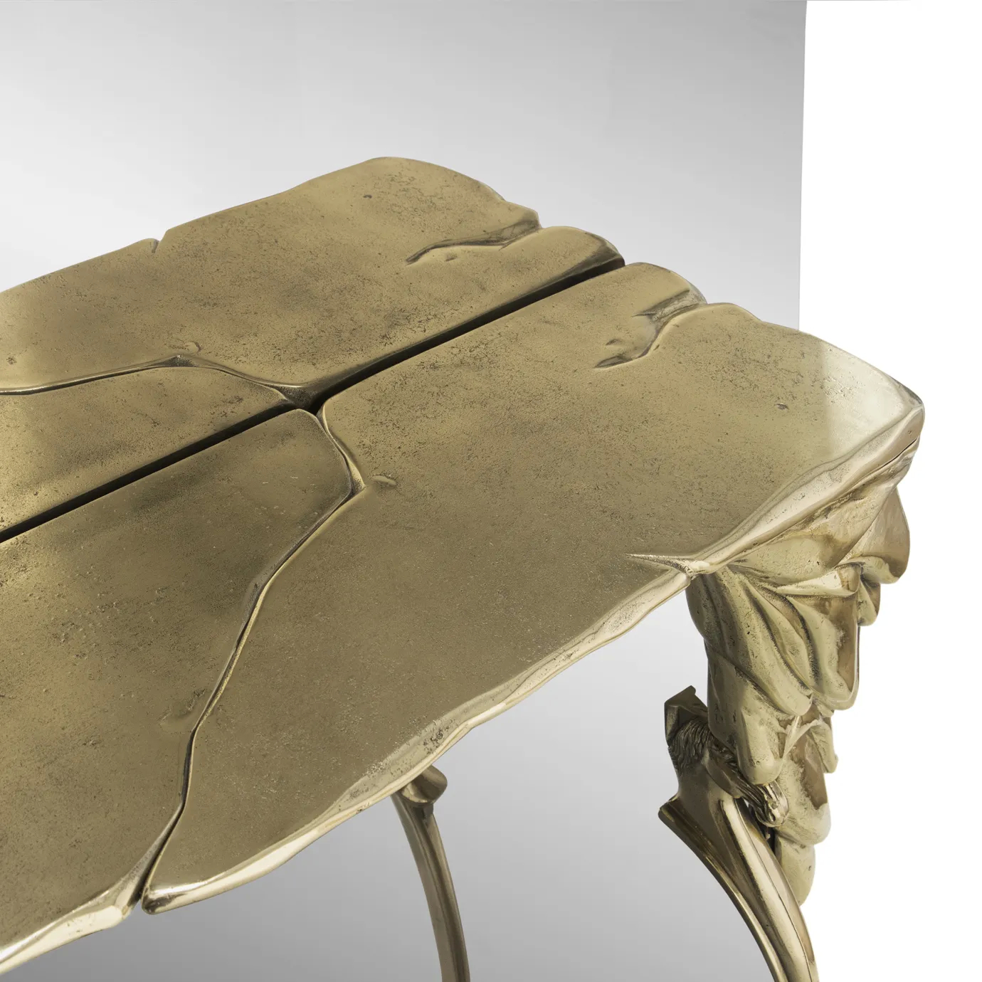 Close-up of Lumiere Console’s gold console table, showcasing its detailed, sculptural design and reflective surface.
