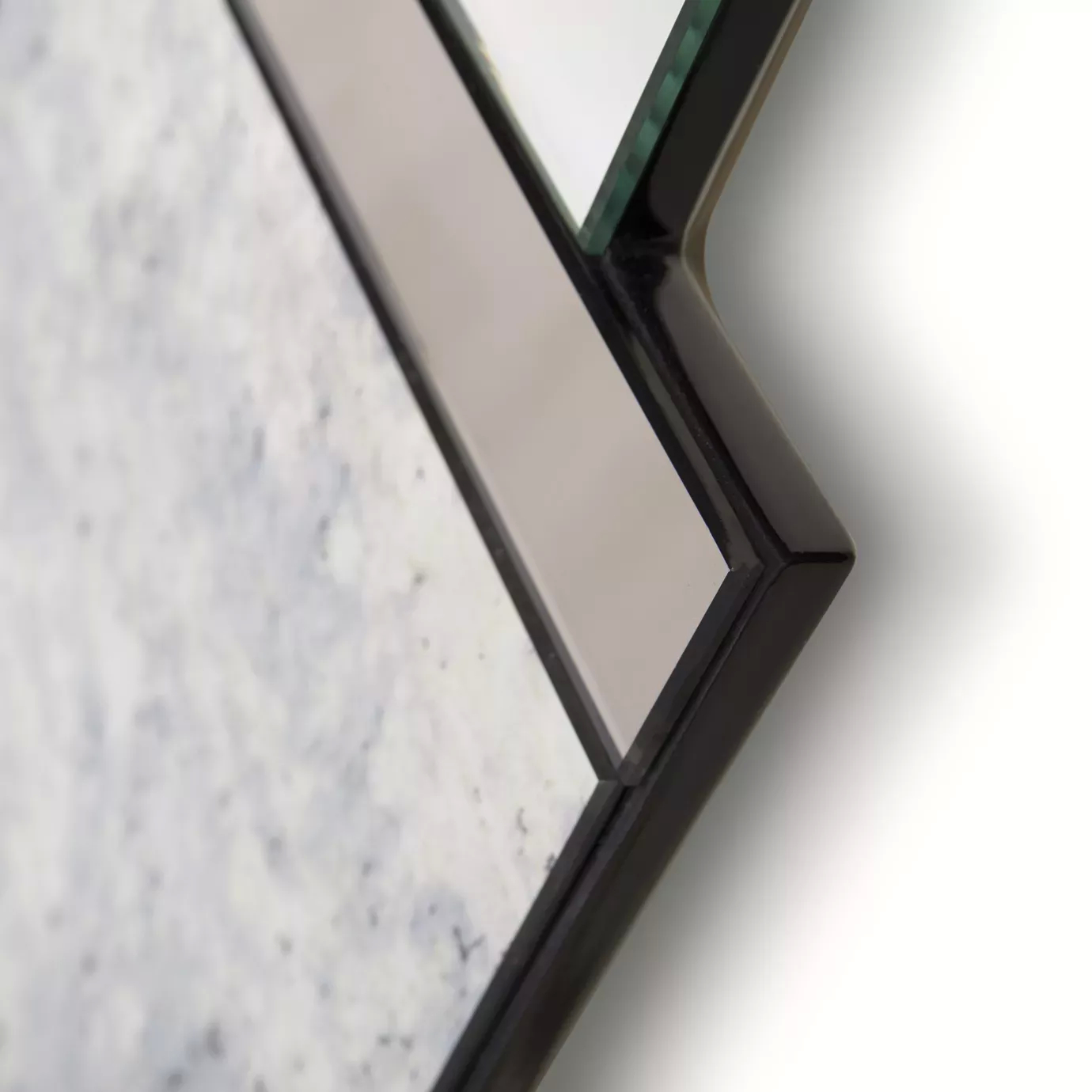 Elegant close-up of the mirrored details and dark frame of the Lemprica Mirror.