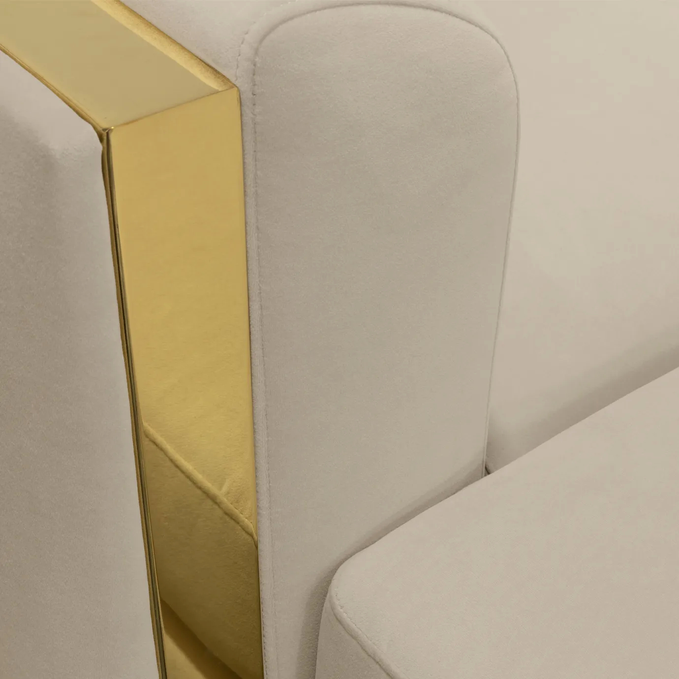Detailed view of sofa armrest with polished brass and smooth velvet upholstery.