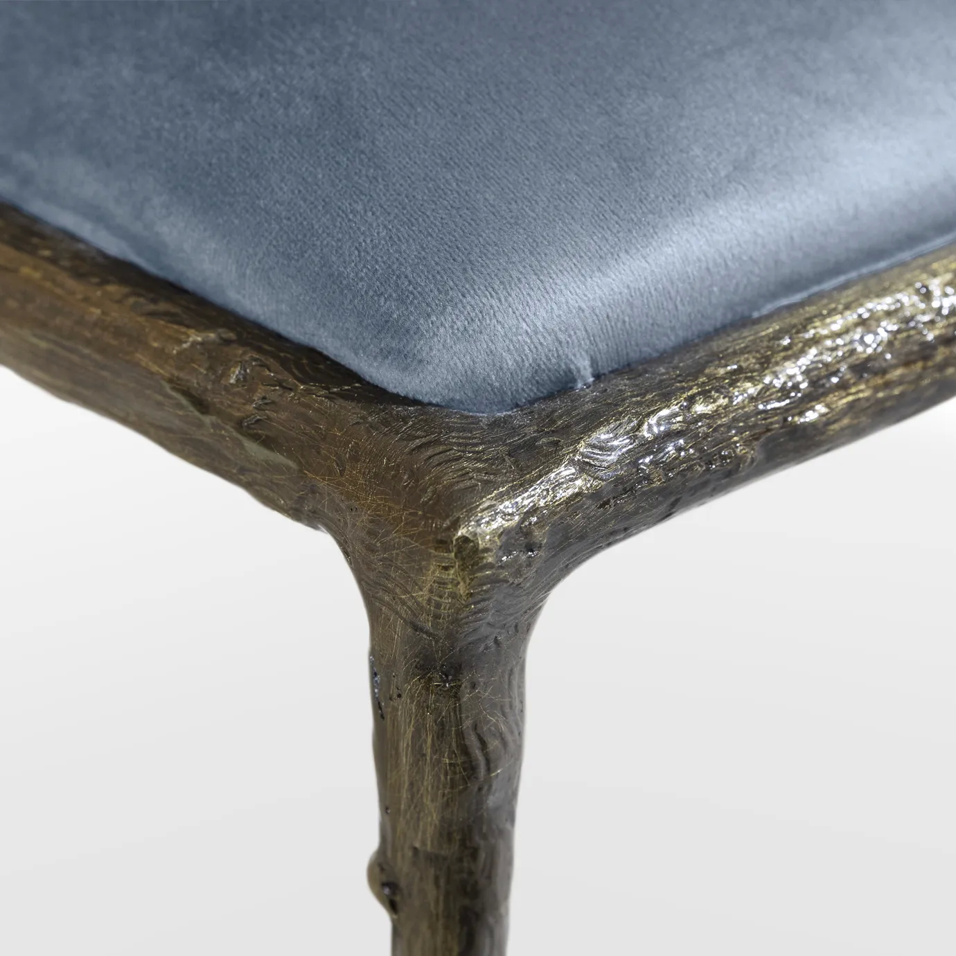 Detailed view of the Enchanted Dining Chair’s elegant aged brass backrest that resembles branches, combining with the blue upholstery.