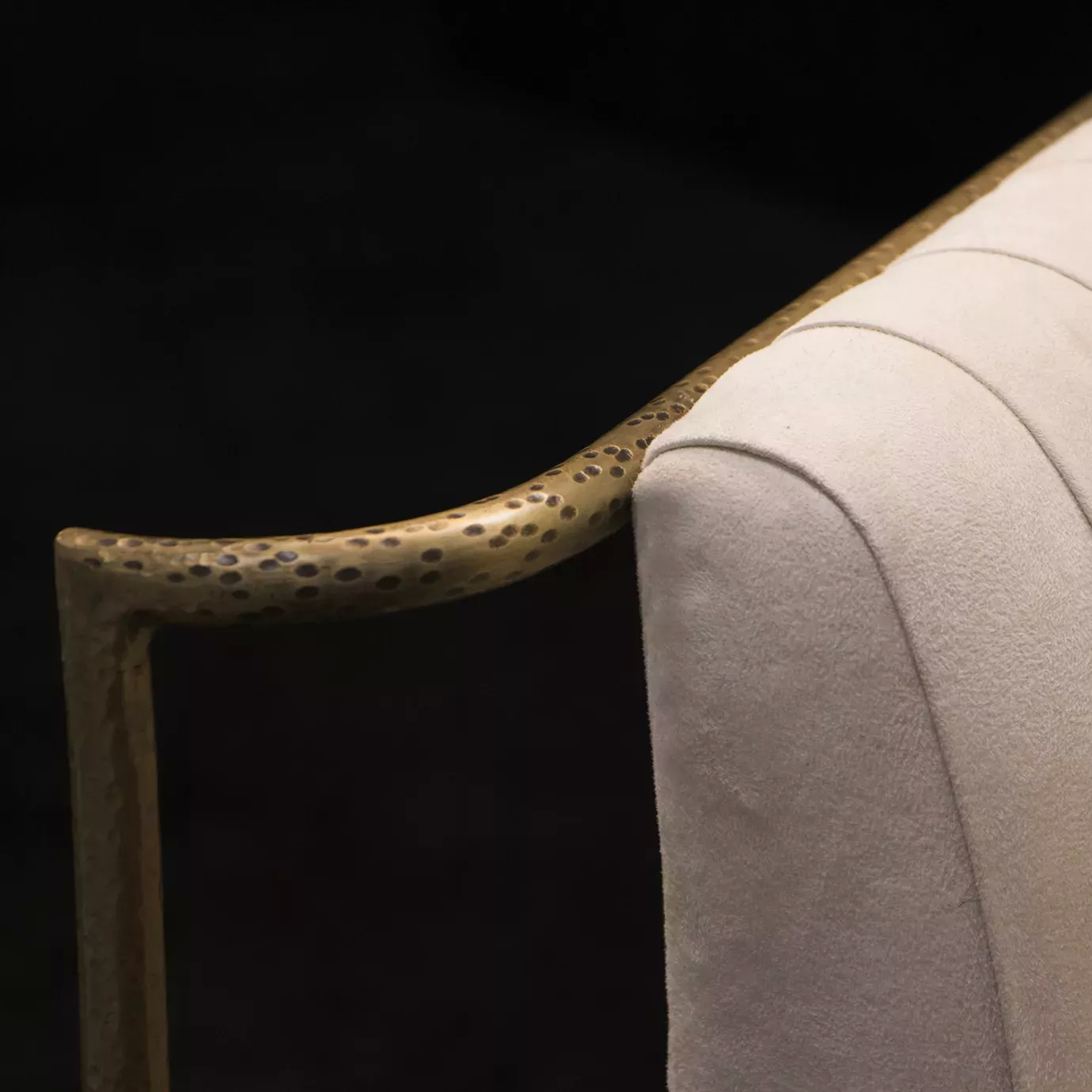 Elegant close-up of the textured golden metal frame and cream fabric of the Desire Chair.
