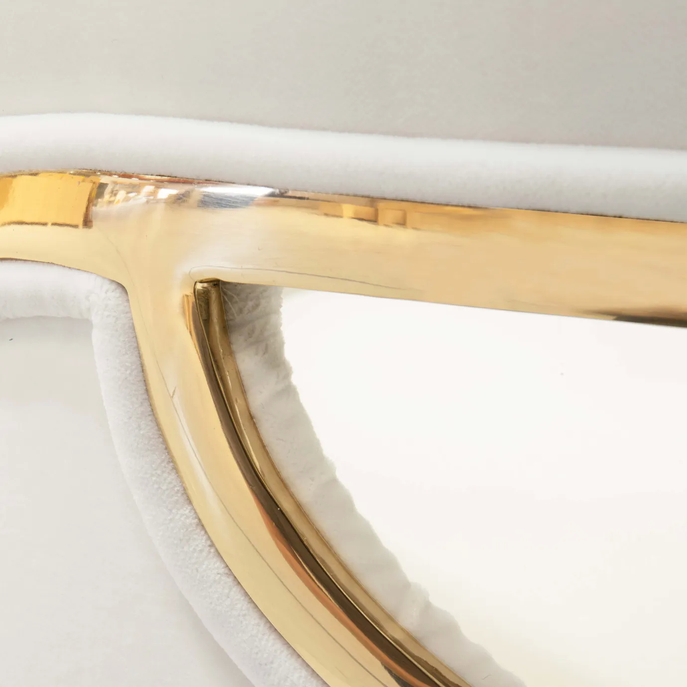 Angled close-up of the Chandra Dining Chair in white by KOKET, emphasizing the elegant curvature of the backrest and the reflective brass detailing.