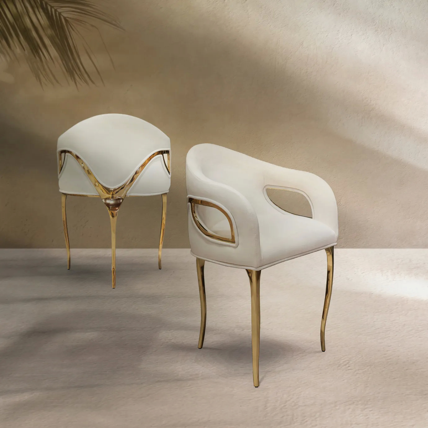 Chandra Dining Chair in white by KOKET, shown in an elegant dining room setting, featuring its sleek brass legs and curved backrest with plush upholstery.