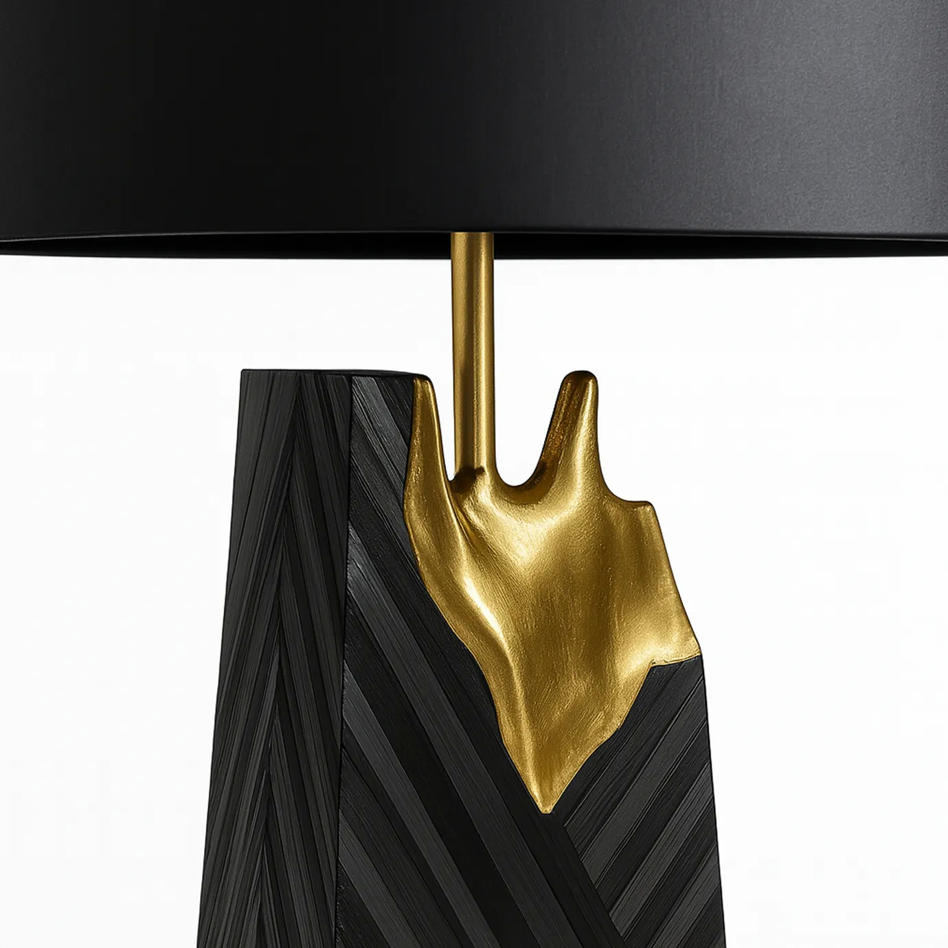 A close-up of the luxurious Gild Table Lamp, showcasing its textured black base, the prominent gold metallic accent, and part of the black shade.