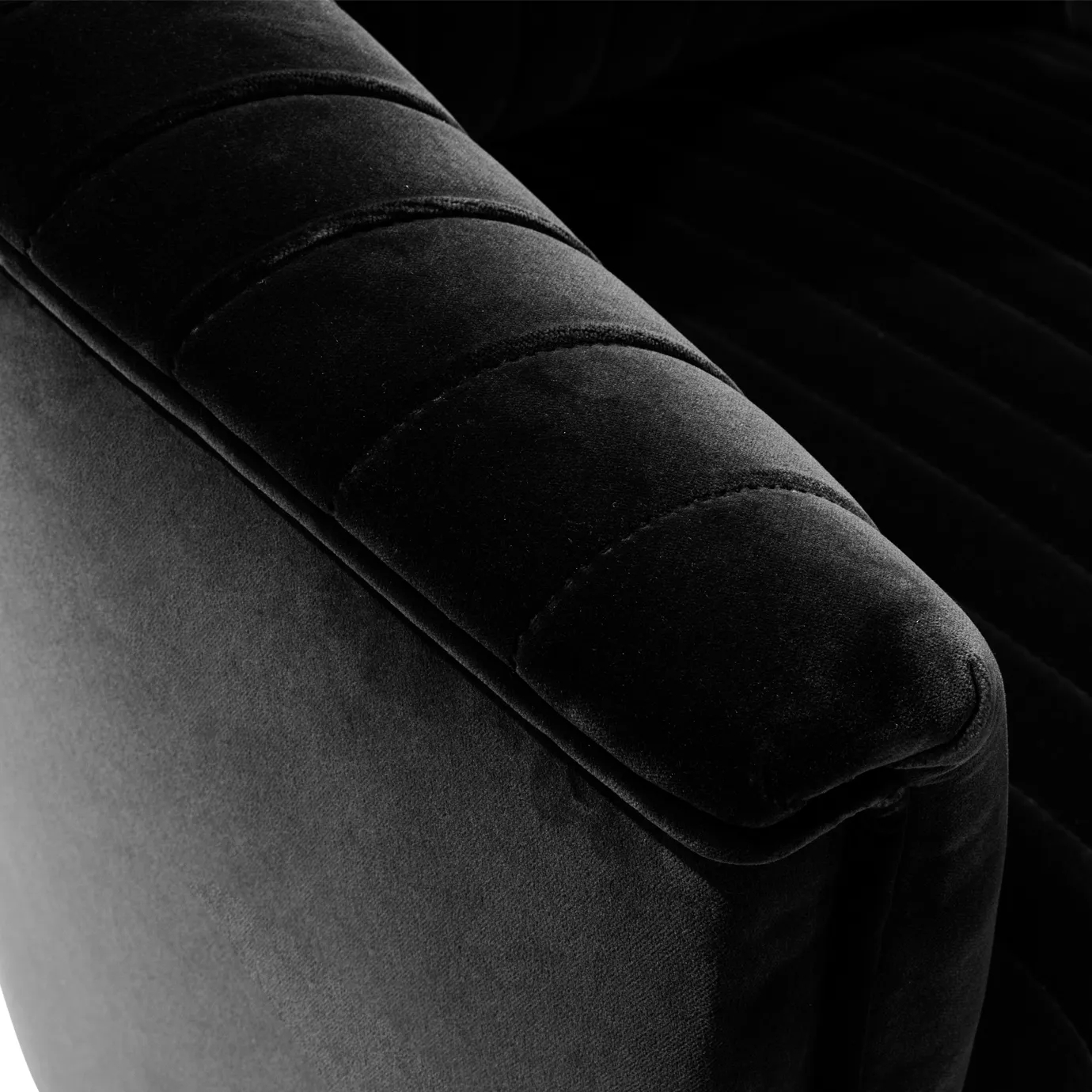 Elegant close-up of the pleated detail of the black velvet of the Mia Armchair.