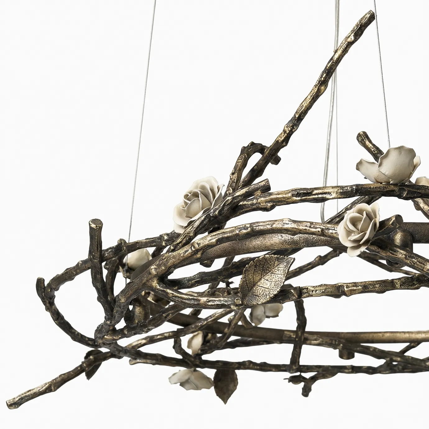 Rose Round Chandelier in aged brass with sculptural branches, metallic leaves, and cream rose-shaped accents, suspended by thin wires in a modern interior.