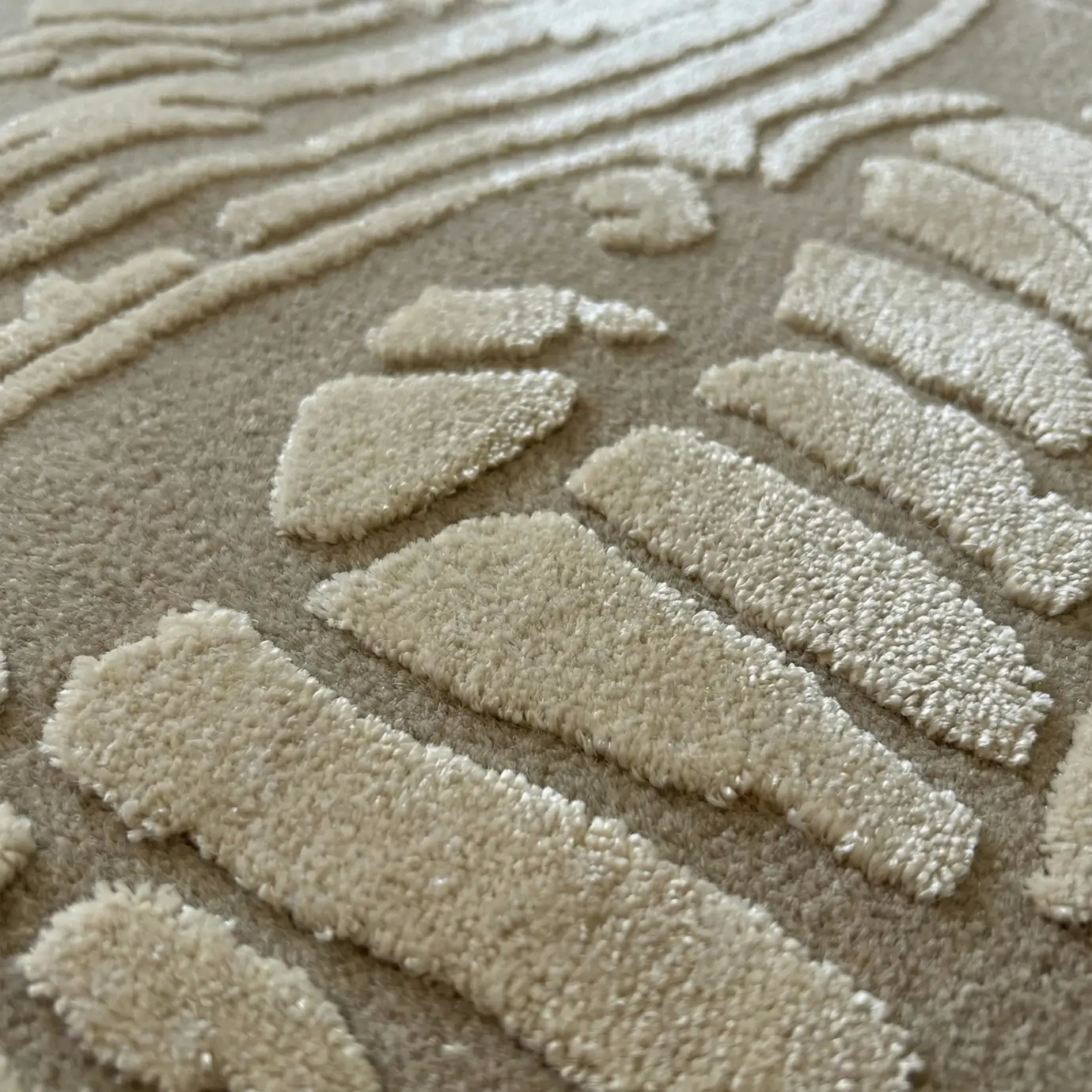 Close-up of the KOKET Flora Sand luxury rug, highlighting the premium hand-tufted relief texture and the sophisticated neutral beige color palette.