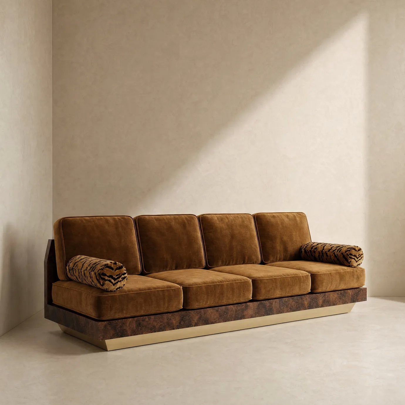 Eileen sofa by KOKET in a sunlit plaster room, amber velvet, tiger-print bolsters, walnut burl base on an aged brass plinth.
