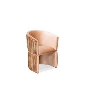 Elegant Cuff Chair upholstered in peach-toned velvet with pleated details and a wraparound design.