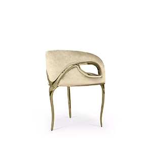 Side view of the Chandra Chair, notable for its three golden legs and cream velvety upholstery, creating an elegant combination.