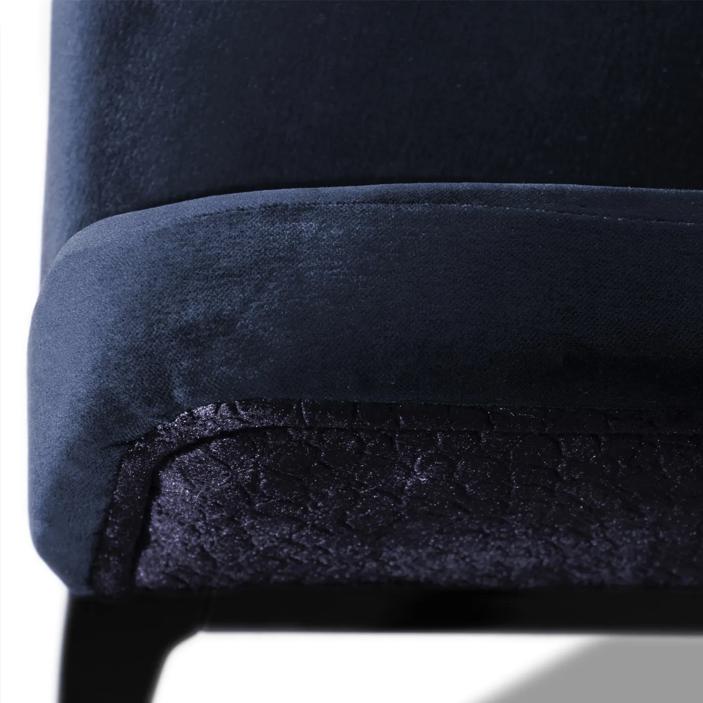Elegant close-up of the contrast between the deep blue velvet and the textured side detail of the Anastasia Dining Chair.