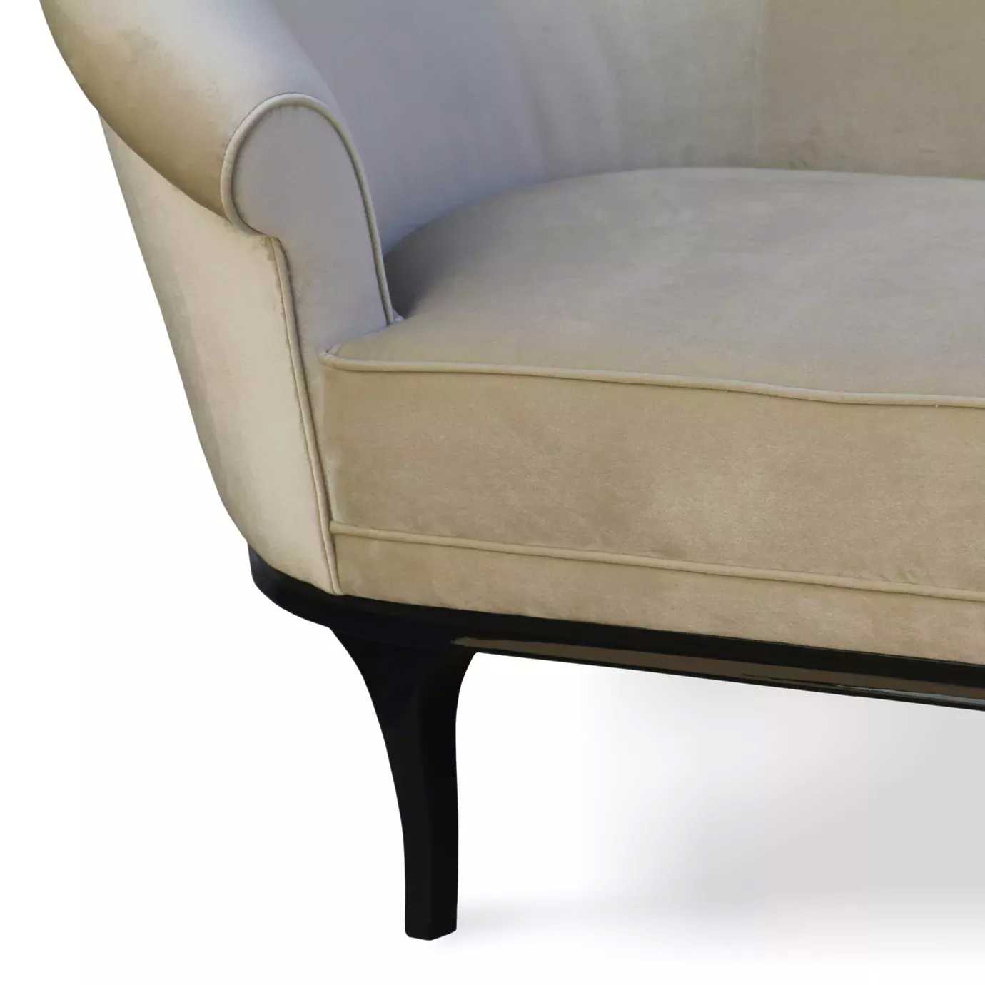 A close-up of the Colette Sofa shows its soft, light-colored upholstery, curved armrest detail, and sleek, dark wooden leg.