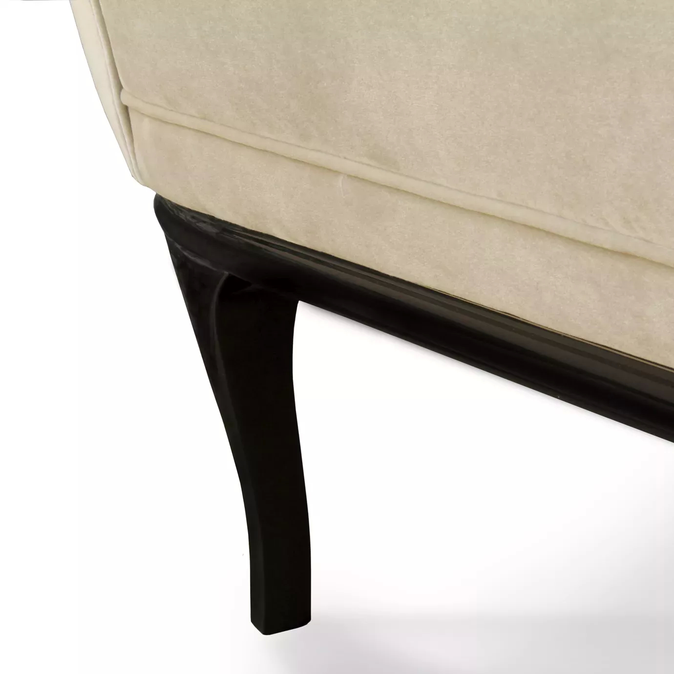 A close-up of the Colette Sofa shows its soft, light-colored upholstery and the elegant curve of its dark, sleek wooden leg.
