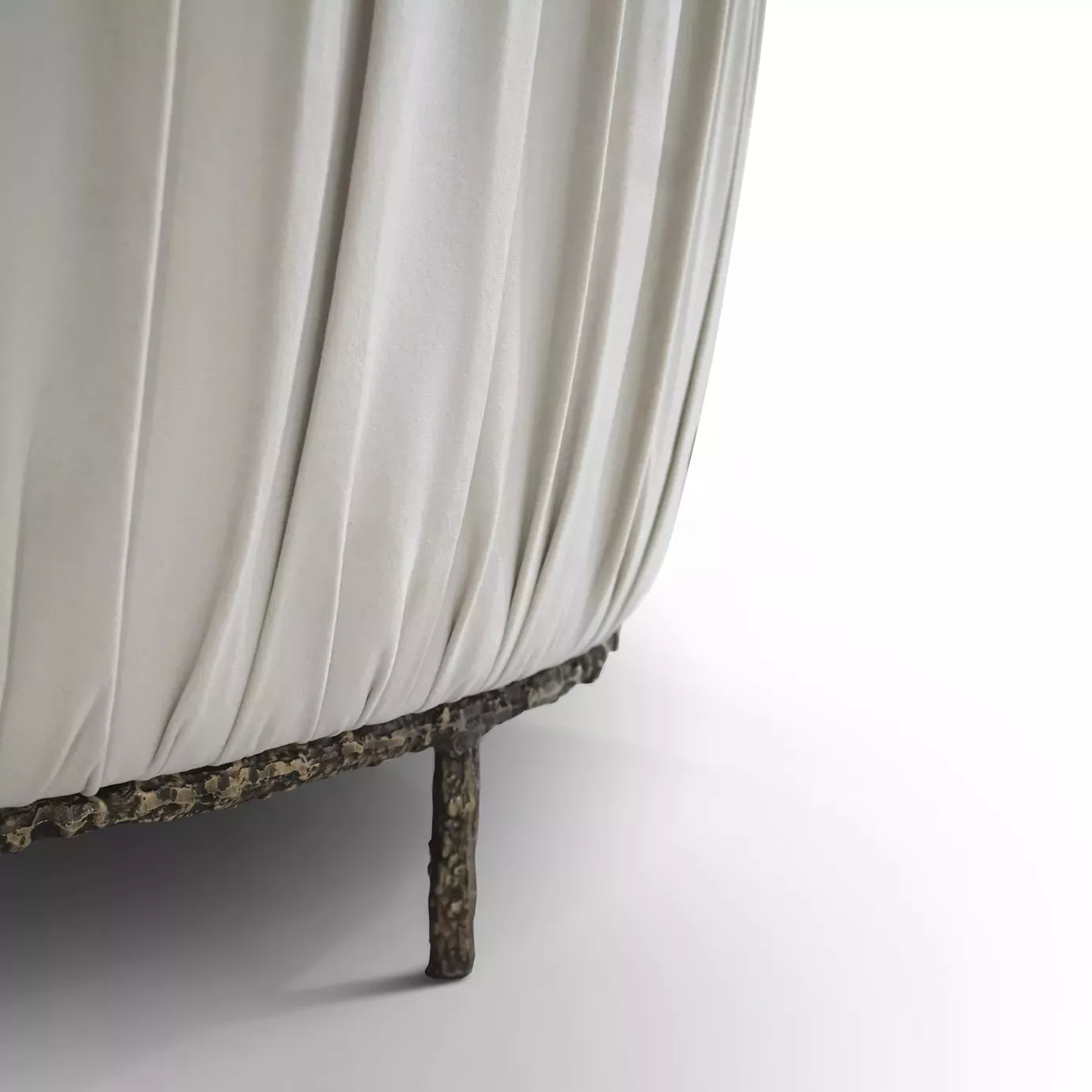 Elegant close-up of the pleated detail of the cream fabric and the ornate golden metal base of the Vamp Sofa