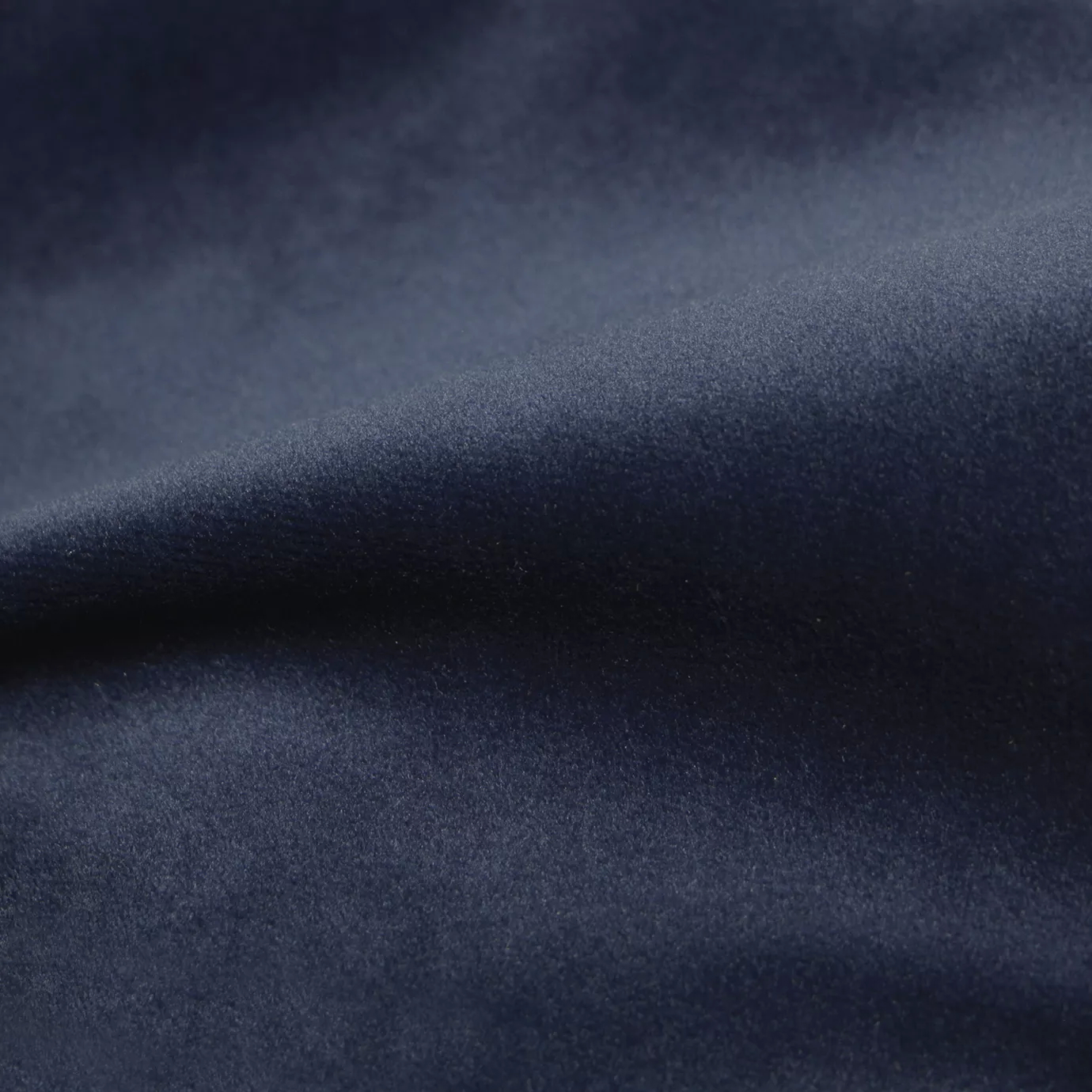 Elegant close-up of a Cozy Velvet Ink Blue fabric swatch in a deep and rich ink blue tone, showcasing its velvety texture and the gentle folds that give it a luxurious feel.