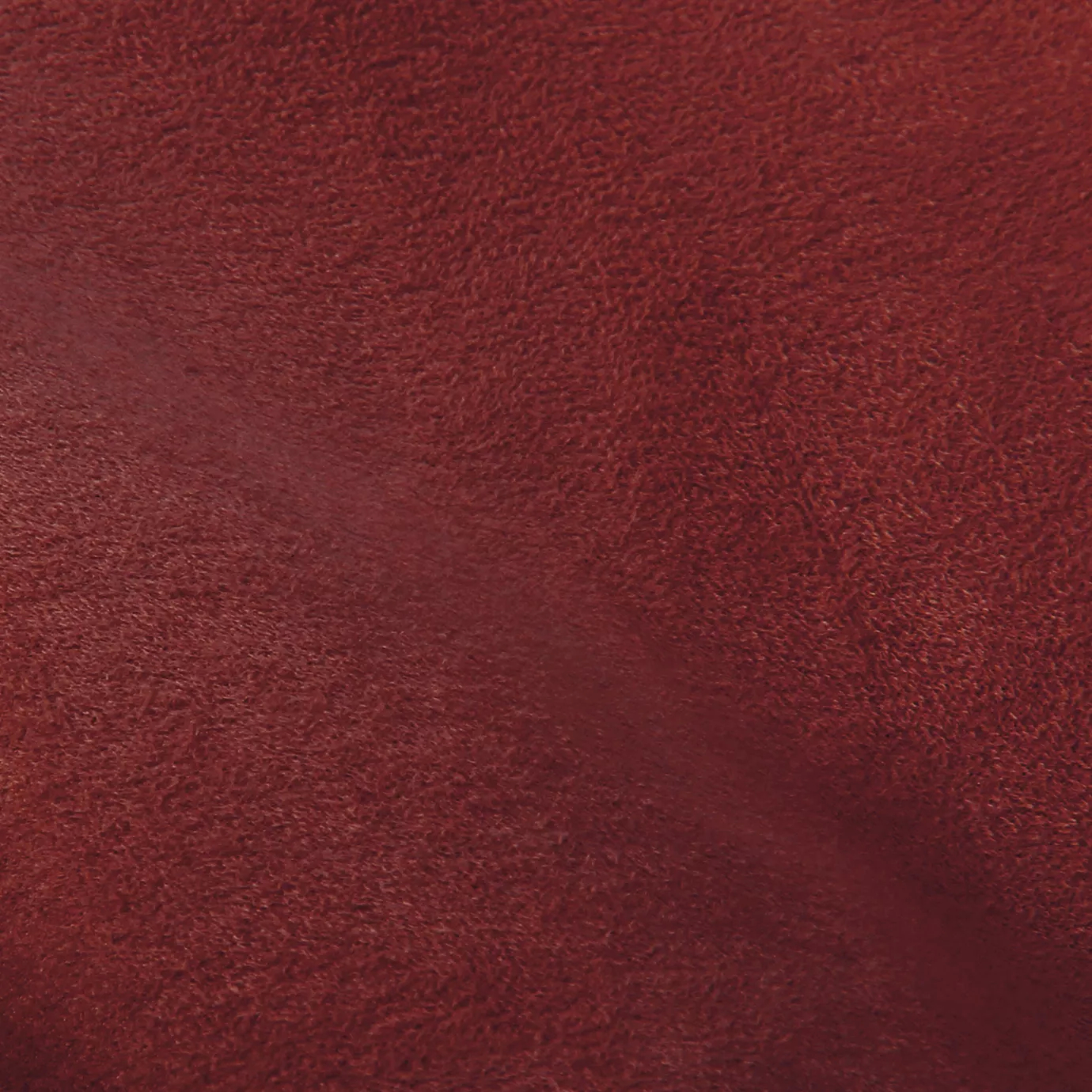 Soft close-up of an Ultra Suede Cranberry fabric swatch in a rich and vibrant cranberry red tone, showcasing its delicate texture and a gentle touch that gives it a feeling of comfort and natural elegance.