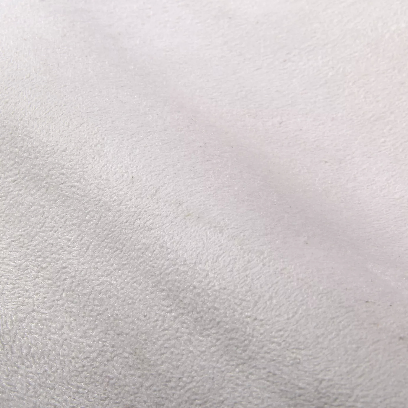 Soft close-up of an Ultra Suede White fabric swatch in a pure and soft white tone, showcasing its delicate texture and a gentle touch that gives it a feeling of comfort and understated elegance.