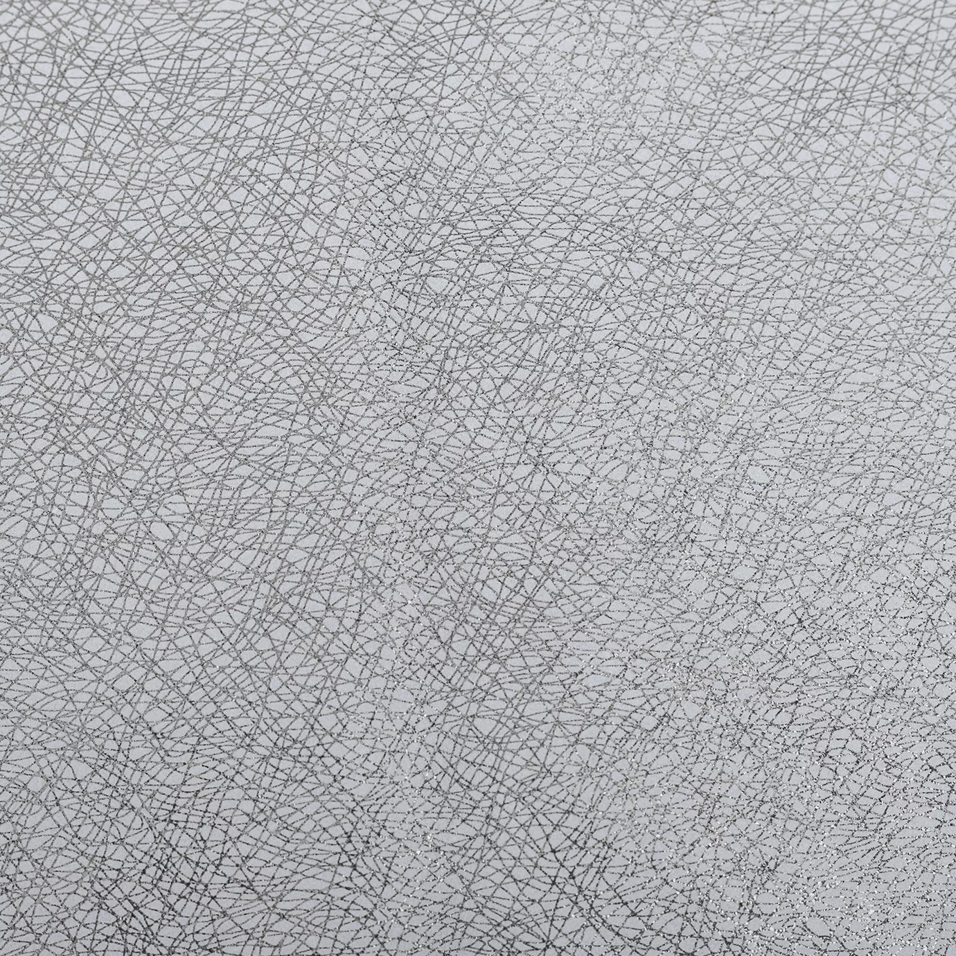 Close-up of a Glamour Silver Pewter fabric swatch with an abstract pattern of fine silver lines interwoven on a light base with a slightly grayish tone, showcasing its unique texture and a subtle metallic sheen that gives it a feeling of modernity and sophisticated elegance.