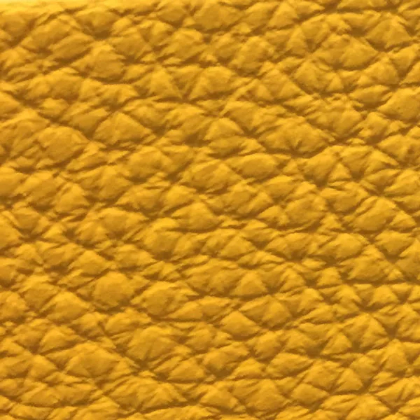 Close-up of a Harbor Sunflower fabric swatch in a vibrant sunflower yellow tone with texture, showcasing its raised areas and grooves that give it a cheerful and elegant feel. The soft sheen highlights the depth of its texture.