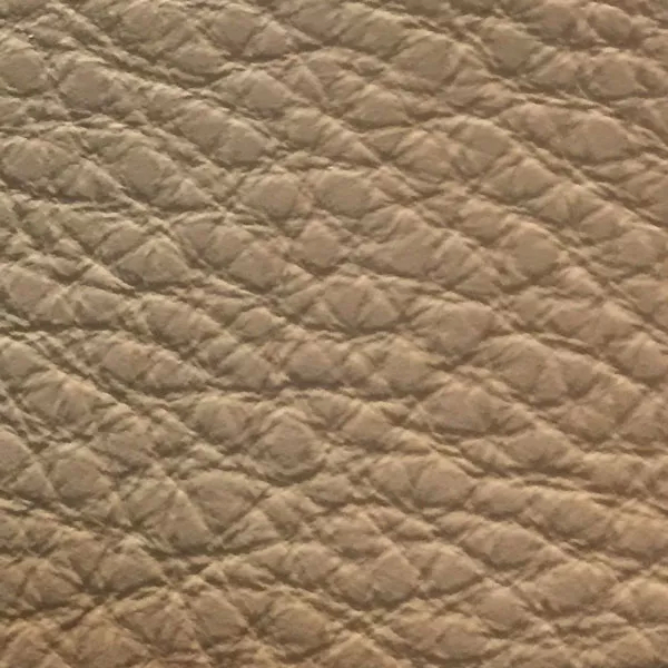 Close-up of a Harbor Tannin fabric swatch in a light beige tone with texture, showcasing its raised areas and grooves that give it a natural and elegant feel. The soft sheen highlights the depth of its texture.