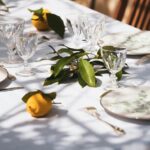 Ultimate Summer Outdoor Dining Guide A outdoor dining space, set with a white table. There are plates, glasses and lemons on top of the table.
