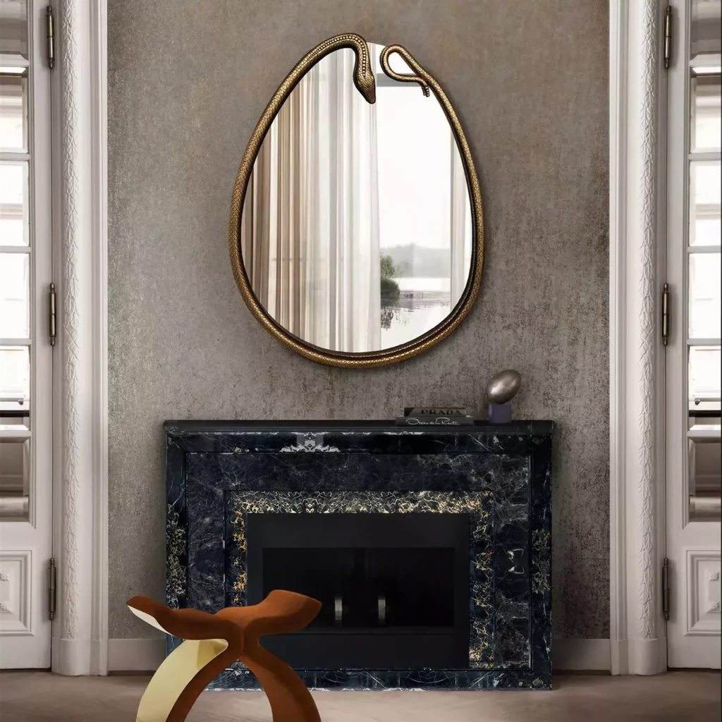 A pear-shaped mirror with a golden frame resembling a serpent, above a fireplace.