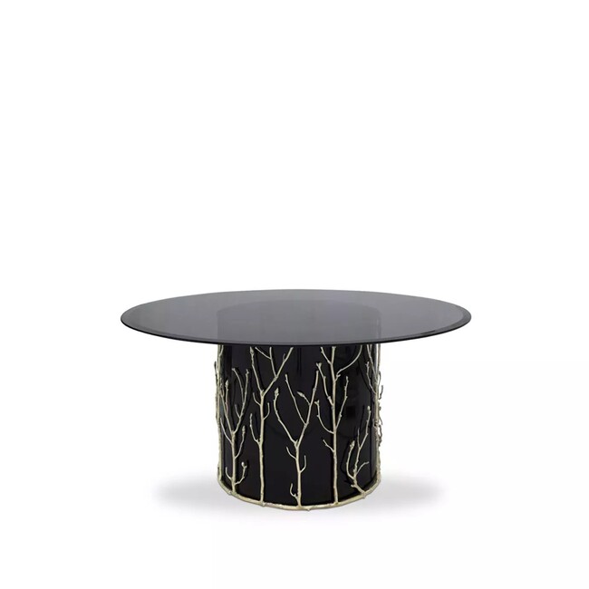 Featuring a smoked glass tabletop, the Enchanted Dining Table has a black structure adorned with intricate aged brass details, resembling branches.