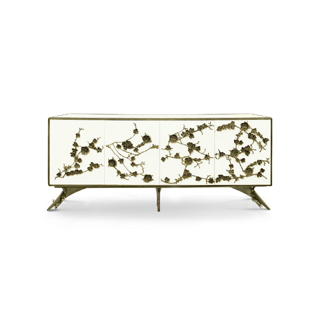 The Spellbound Lacquer Cabinet features a white structure adorned with a golden frame and elegant golden flower-shaped details along its four front doors.