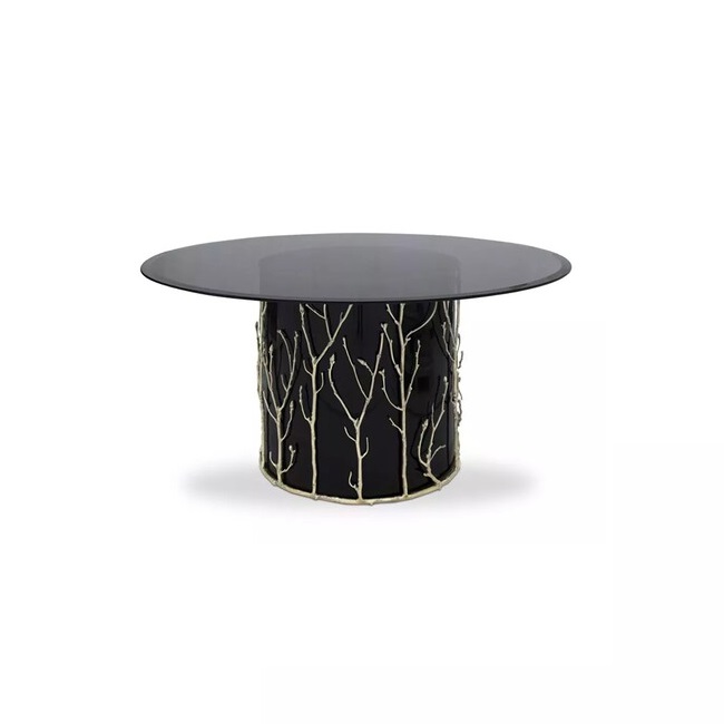 Featuring a smoked glass tabletop, the Enchanted Glass Top Dining Table has a black structure adorned with intricate aged brass details, resembling branches.