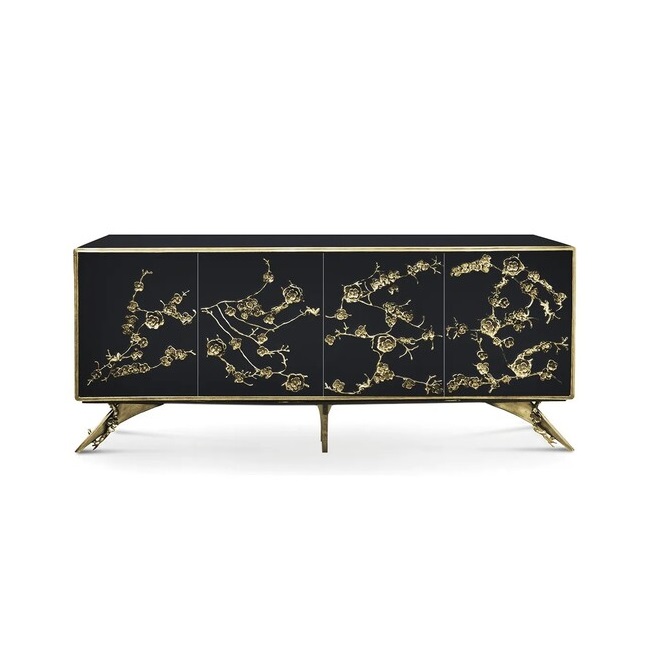 The Spellbound Lacquer Armoire features a black structure adorned with elegant golden flower-shaped details along the bottom of the front doors.