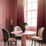 Round marble dining table with sculptural chairs in a cinematic, blush-toned interior by KOKET