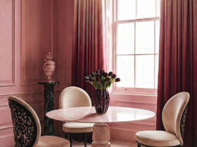 Round marble dining table with sculptural chairs in a cinematic, blush-toned interior by KOKET